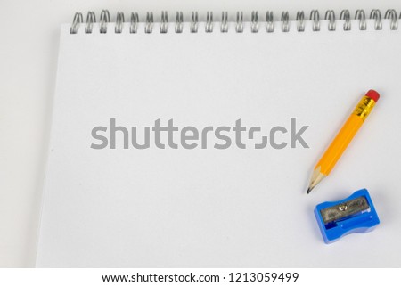 Notebook for taking notes and pencil on the office table. Accessories for quotation and memorization needed in accounting. White background.