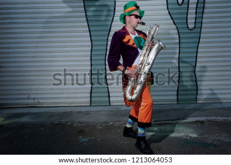 Saxophone player jazz music instrument Saxophonist with Baritone sax on street.