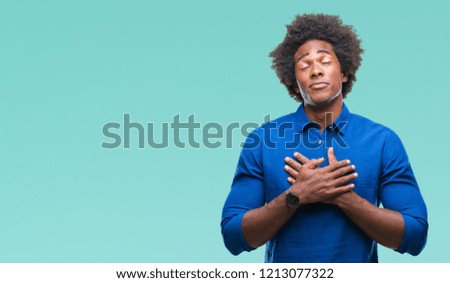 Afro american man over isolated background smiling with hands on chest with closed eyes and grateful gesture on face. Health concept.