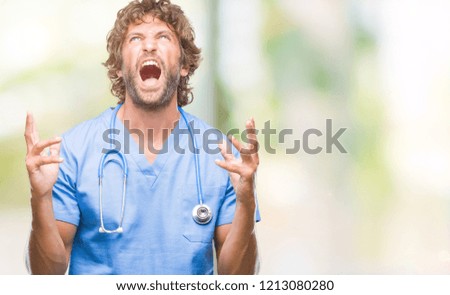 Handsome hispanic surgeon doctor man over isolated background crazy and mad shouting and yelling with aggressive expression and arms raised. Frustration concept.