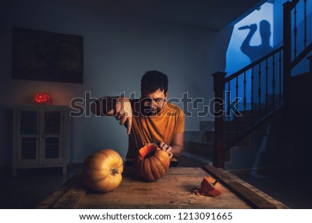 man cutting halloween pumpkin