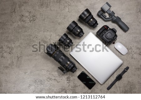 Photography equipment to travel on bare mortar background, DSLR camera,  Lenses, laptop, mouse, gimbal and smart watch