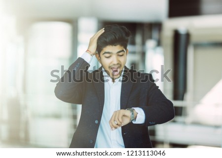Portrait of a business man watching watch with worried emotions of late in office