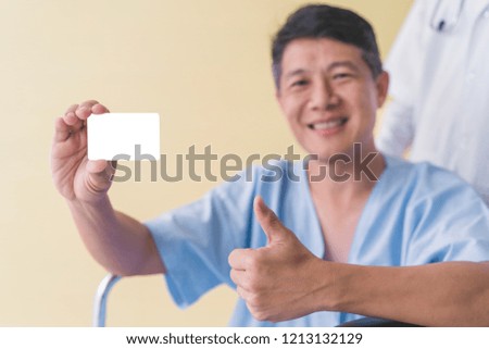 Asian senior patient wheelchair showing white card with thumb.