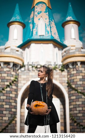 A girl with beautiful make-up walks a hand-pumpkin on a leash in a fabulous park. Halloween creative picture