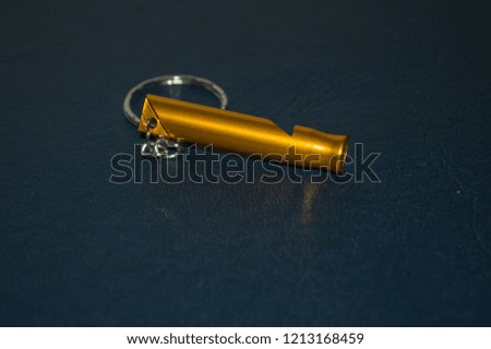 golden whistle on keychain, for adventure Trekking, isolated on blue background