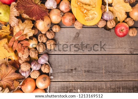 Autumn arrangement of seasonal harvests with colorful leaves. Top view of vegetables and fruits such as apples, pumpkin, walnuts, onions. Free, copy space.