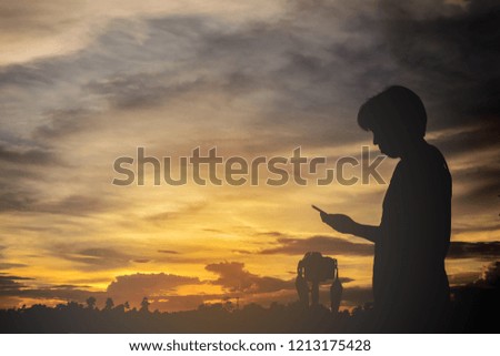 silhouette of man taking pictures with his smartphone at sunset.