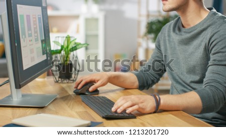 Close-up Shot of Man Using Computer and His Hands Typing on a Keyboard and Using Mouse. In the Background Cozy Living Room.