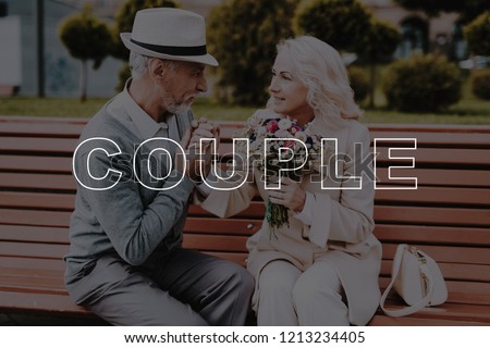 Old Couple. Kisses Hand. Flowers. Two Pensioners. Alley in Park. Bubbly Relationships. Love Story. Sit. Bench. Elderly Man. Woman. Gift. Retired. Happy Together. Leisure Time. Have Fun. Smiling.