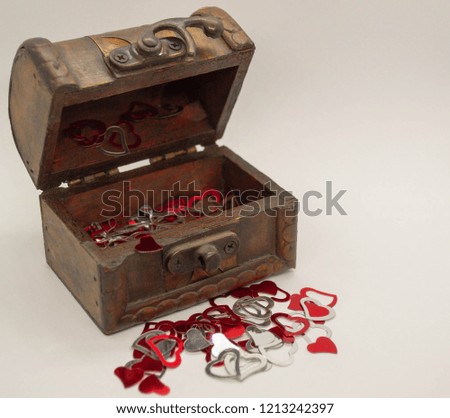 open wooden chest with red and silver hearts inside and on a white background in front. free space for text