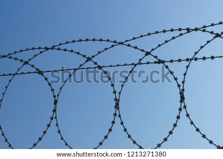 Spiral Bruno-anti-personnel barrier in the form of a cylindrical spiral-to enhance the inaccessibility of the fence against the blue sky