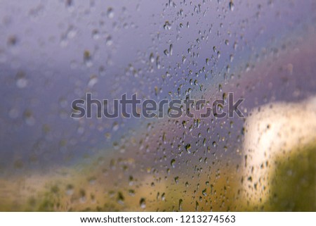 Rain drops on window and rainbow in background