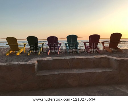 Sunset over the Pacific Ocean with rainbow coloured chairs. Picture taken in El Salvador.
