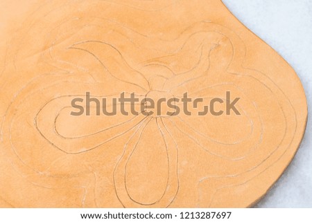 workshop of making the carved leather bag - floral pattern prepared for carving on surface of rough vegetable tanned leather