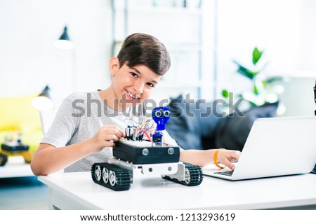 Smart positive boy testing robot while getting ready for engineering classes at home Royalty-Free Stock Photo #1213293619
