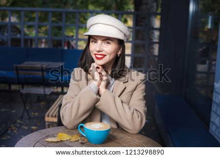 Beautiful smiling girl in a hat with a cup of coffee
