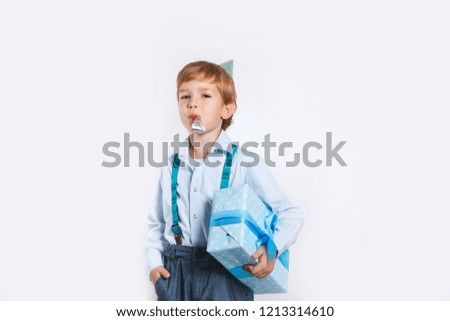 Cute little smiling boy in birthday cap holding present. Holidays concept.