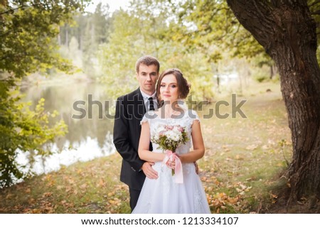 Wedding couple. Bride and groom are embracing in the autumn park against the background of the lake. Newlyweds