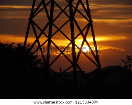 
Bright, contrasting landscape with a sunset sky, clouds, a silhouette of an electrical tower and electric wires