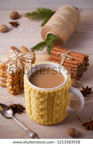 Knitted yellow cup with hot winter drink, cookies, cinnamon, decorations. Cozy
