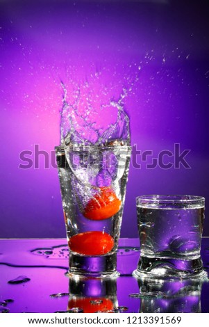 fall of two cherry tomatoes inside the glass