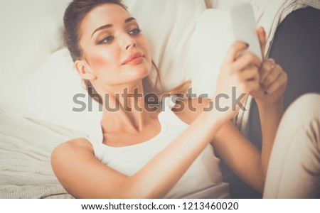 Happy brunette taking a photo of herself with her mobile phone in bedroom