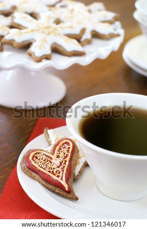 Heart shaped gingerbread cookie, decorated for Christmas, and a cup of coffee.