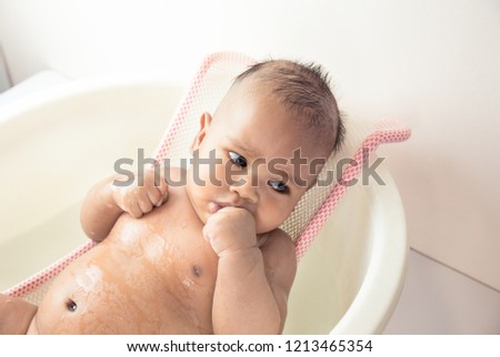 cute asian baby boy taking a shower in a bathtub