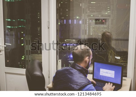 The system administrator with a laptop works in a modern data center. The duty engineer sits in a networked server room. Dispatch service of internet provider.