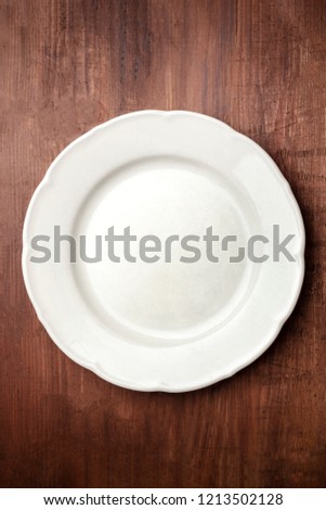 White plate, shot from the top on a dark rustic wooden background with copy space