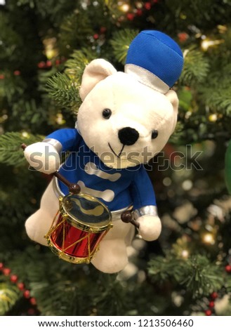 Cute plush white bear Holiday ornament hanging on lit Christmas tree