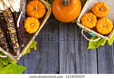 seasonal display of leaves, pumpkins and corn against a wooden background.