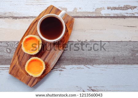 Egg tart and a cup of coffee on wooden background