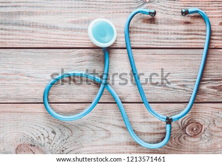 A blue stethoscope on a wooden table. Medical cardiology equipment. Top view.