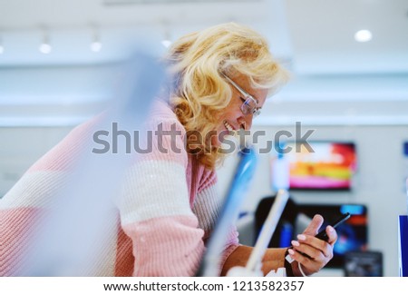 Beautiful senior woman portrait at tech store. Looking for a new smart phone.