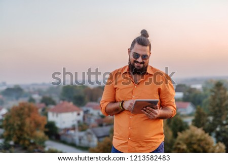 Young urban man standing at the top of the building holding tablet. 