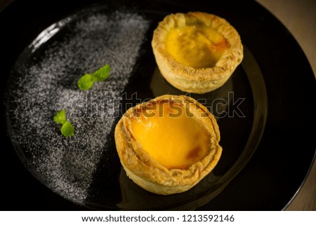 Egg tart, traditional Portuguese dessert on black plate, selective focus, copy space