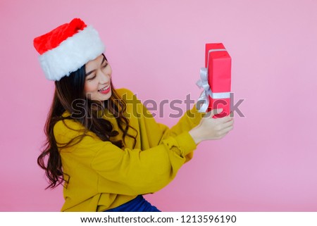 posing asia woman wearing long sleeve clothes on pink background with Santa Claus hat and red present holding in hand, holiday in festive Christmas or X'mas and happy new year concept, Winter fashion