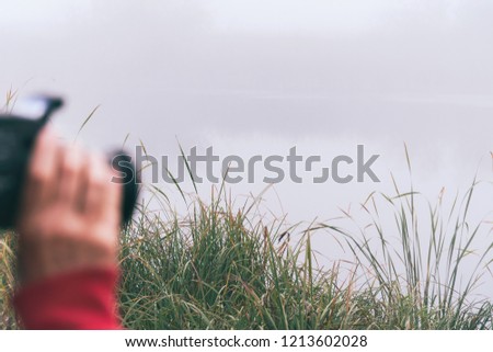 Woman photographer photographs the fog on the lake. Selective focus