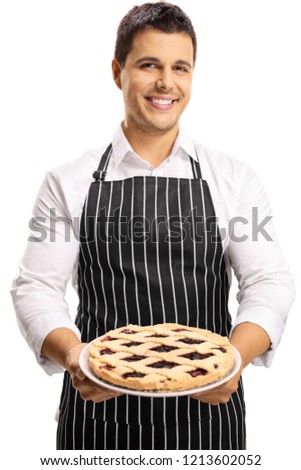 Handsome young man with an apron holding a cherry pie isolated on white background Royalty-Free Stock Photo #1213602052