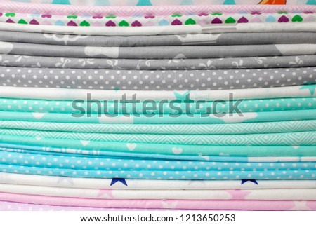 lots of bundles of different verities of new fabric in many color collections kept on the shelf of a local store in Asia 