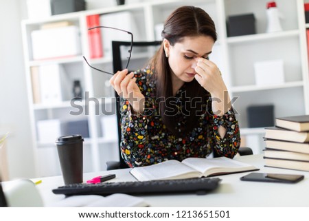 A young girl sitting in the office at the computer Desk and working with a book.