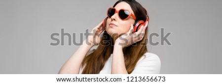 Portrait of emotional beautiful plus size model in headphones and sunglasses standing in studio looking away listening to music