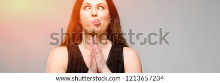 Emotional smiling happy plus size model standing in studio looking in camera talking on phone with friend