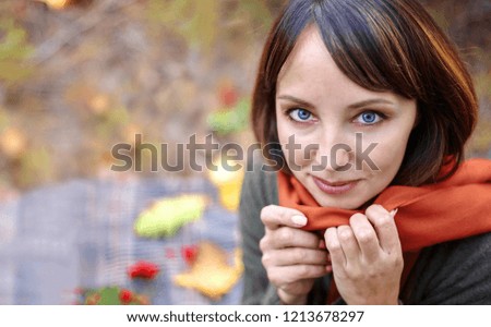 Portrait of a beautiful brunette in an autumn park. Beautiful brunette lies on autumn foliage in the park