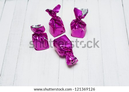 shiny tinfoil wrapped bonbons on white wooden