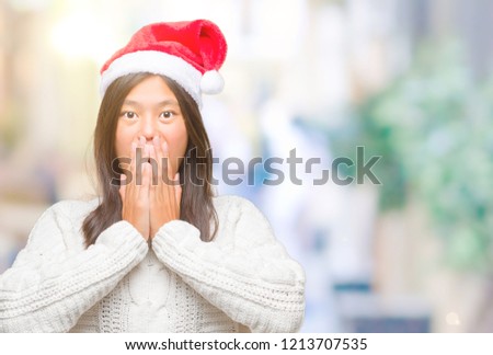 Young asian woman wearing christmas hat over isolated background shocked covering mouth with hands for mistake. Secret concept.