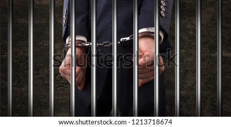 Close convicted man with handcuffs behind grids