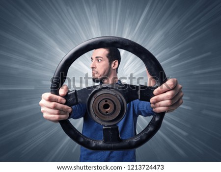 Young man holding black steering wheel with white lines behind him 